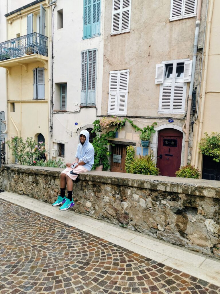 Boy sitting on a stone wall in the old town of Le Suquet in Cannes on the French Riviera