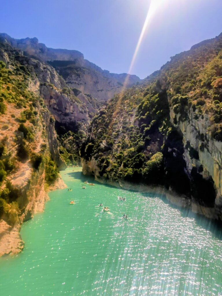 Turquoise water inside Gorge du Verdon surrounded by towering limestone cliffs. 