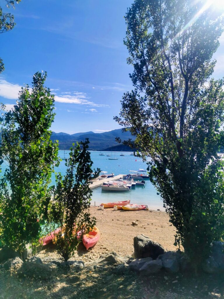 Peaceful view over Lac de Sainte-Croix with turquoise water, boats and surrounding greenery. 