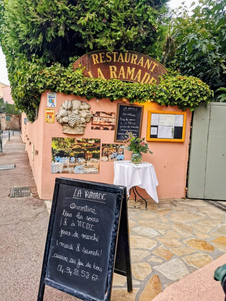 Entrance to La Ramade restaurant in Saint Tropez surrounded by greenery on a warm summer evening.