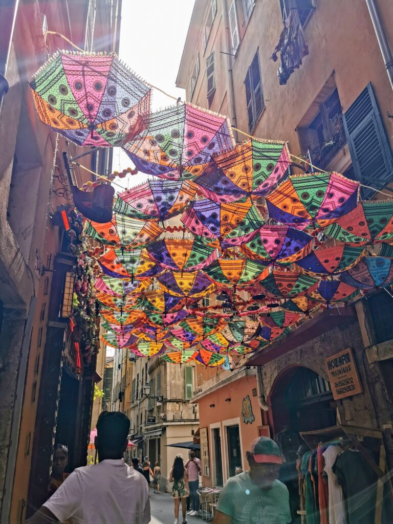 Colourful street in Nice old town with umbrellas hanging above.