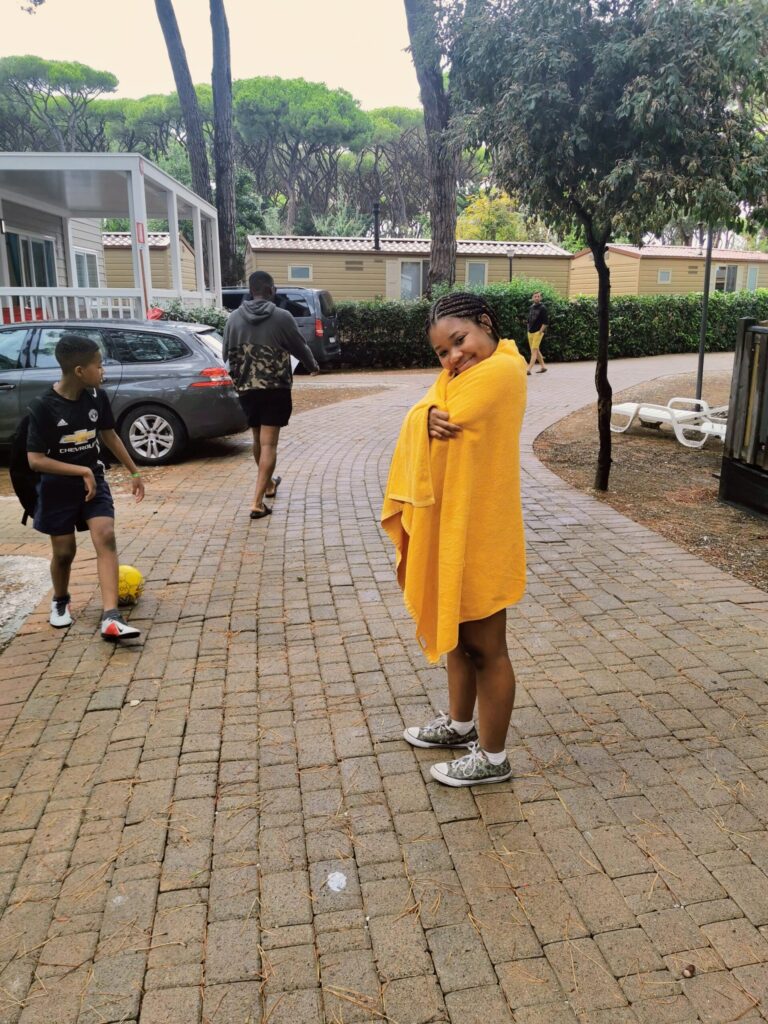 Girl wrapped in a towel standing outside caravan on a sunny day. 