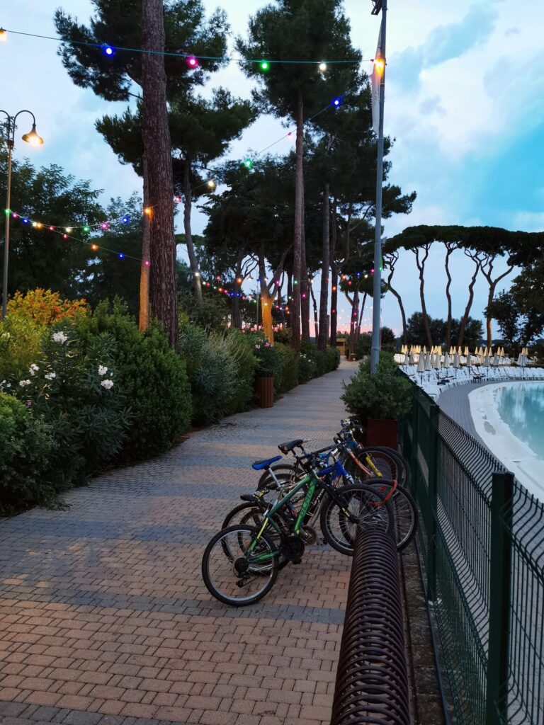 Campsite at dusk with warm lights, bikes nd people walking between caravans.