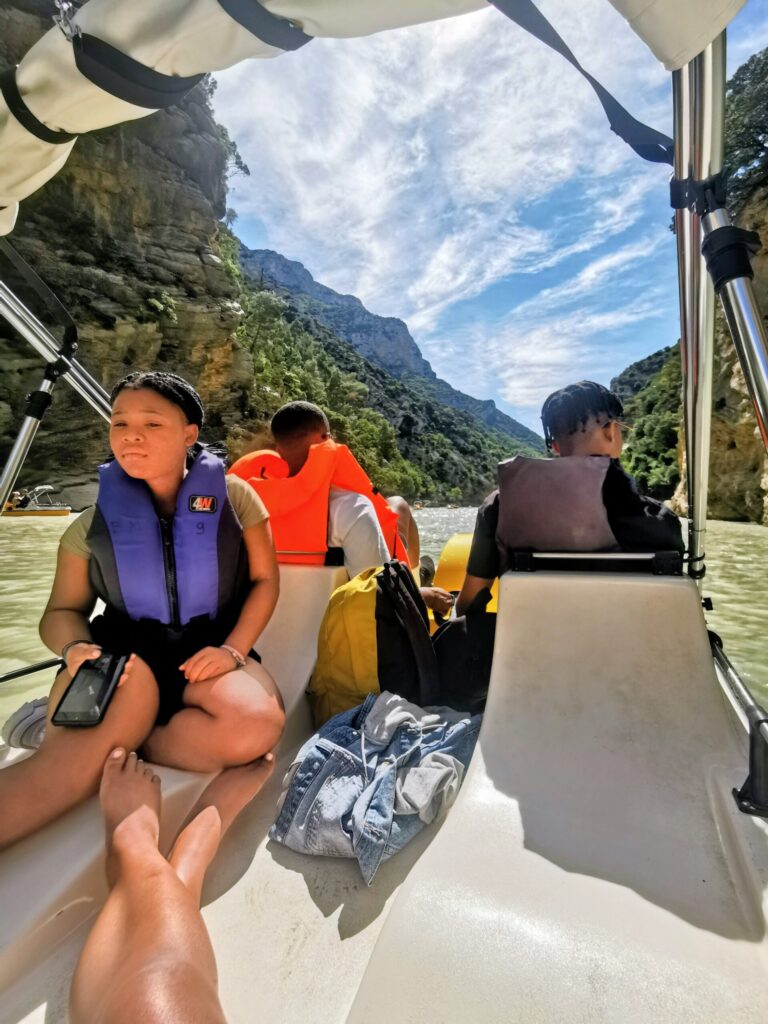 Family kayaking through a river canyon in the South of France, surrounded by rocky cliffs and greenery.