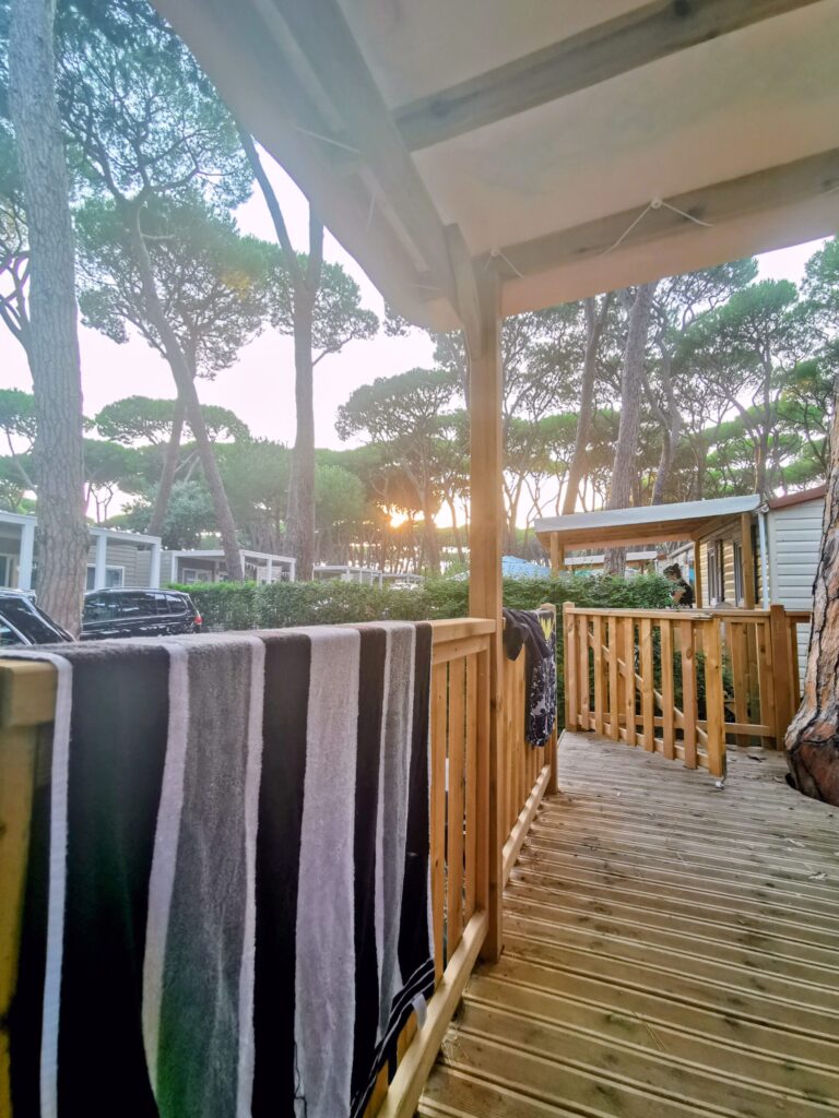 Veranda with striped towels and outdoor seating on a Eurocamp caravan surrounded by pine trees. 