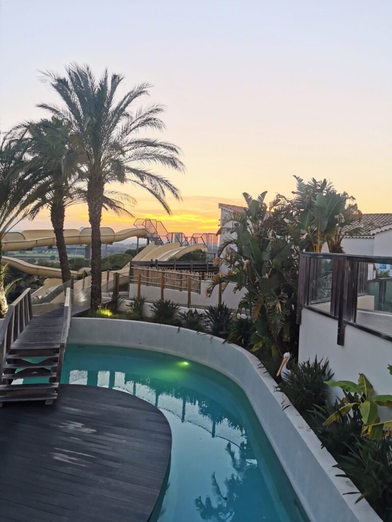 Large Eurocamp waterpark with pools, slides, and palm trees at sunsets, showing the facilities that make family holidays special. 