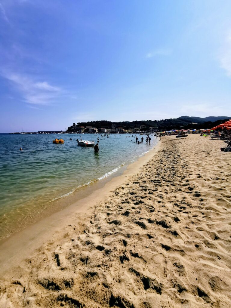 Sandy beach on the Tuscan coast with clear blue sea and families enjoying the sunshine.