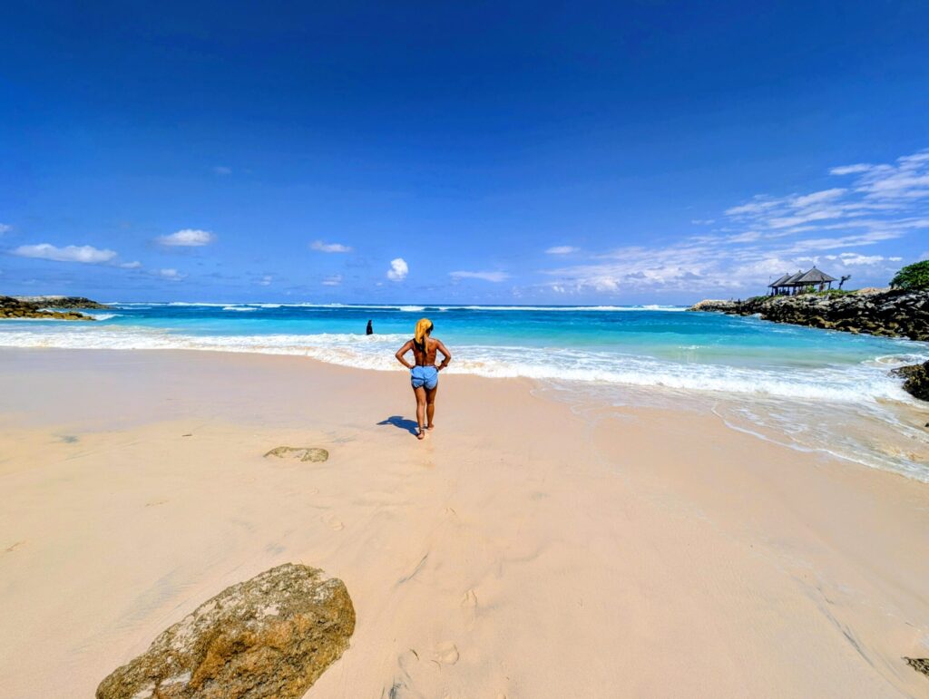Woman walking towards the turquoise sea on a beach in Bali.