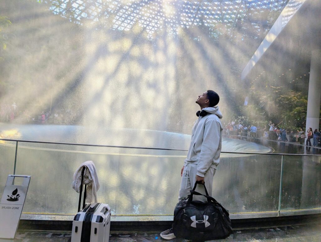 Young traveller with luggage at the Jewel Changi Airport waterfall during our Singapore stopover