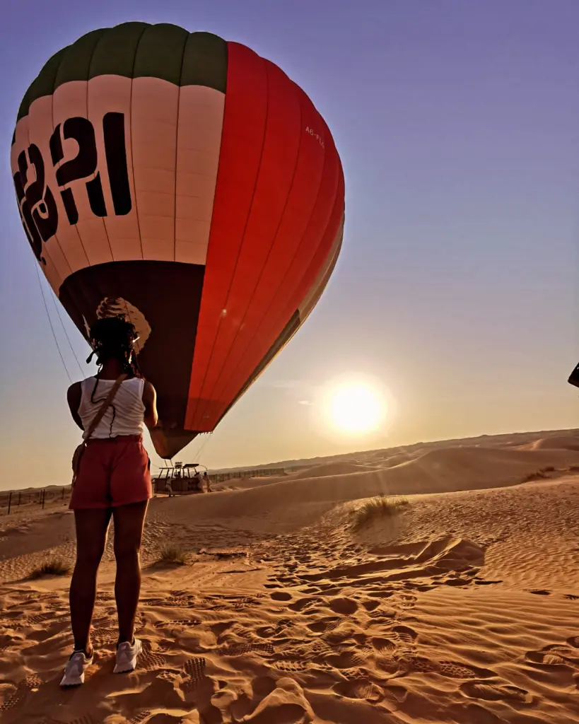 Hot air balloon floating over the desert at sunrise.