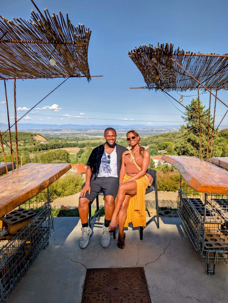 Couple enjoying wine tasting overlooking the Tuscan hills in Italy.