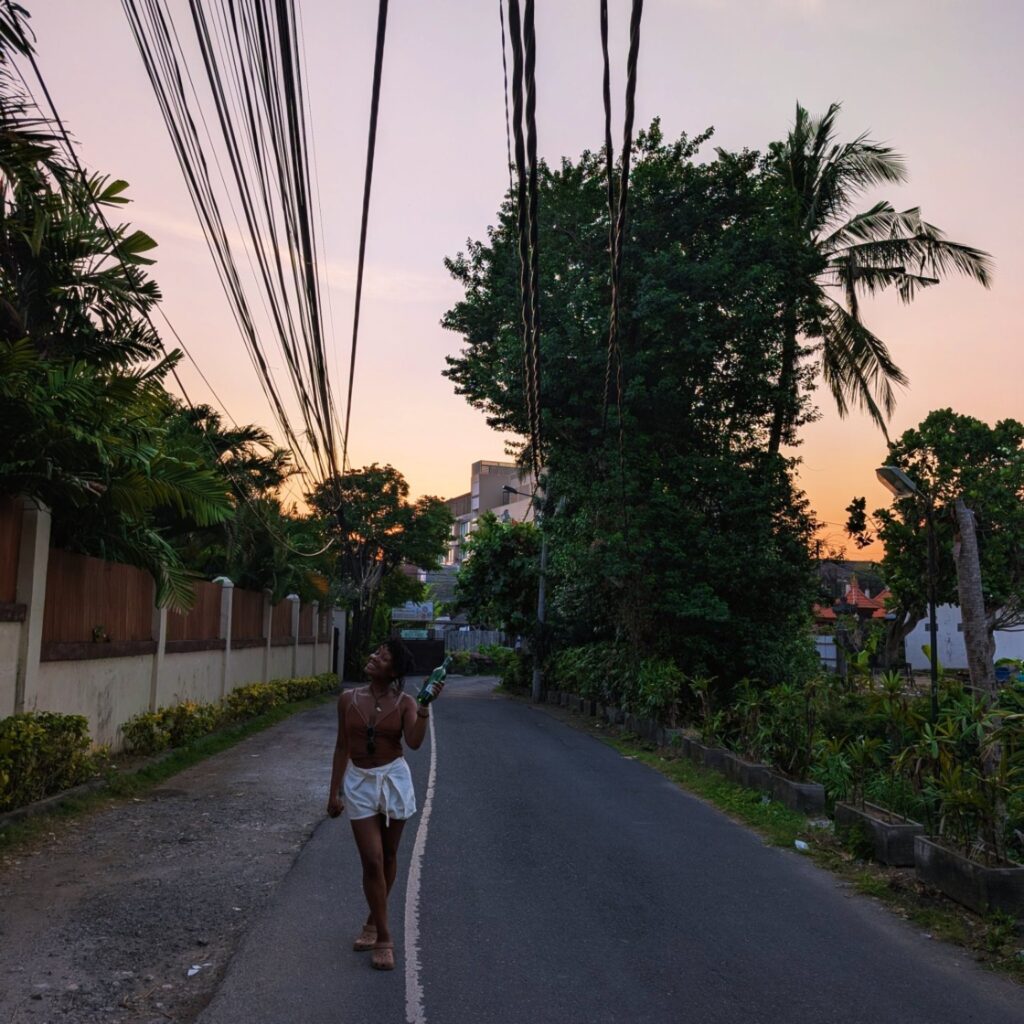 Walking along a quiet street in Bali at sunset, surrounded by tropical trees.